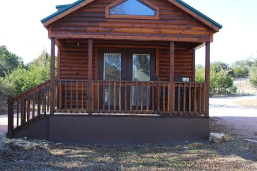 a log cabin with a porch and a window at Log Cabin for Family Glamping Vacation near San Antonio in Pipe Creek