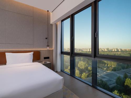 a bedroom with a bed and large windows at Holiday Inn Beijing Daxing Centre by IHG in Beijing