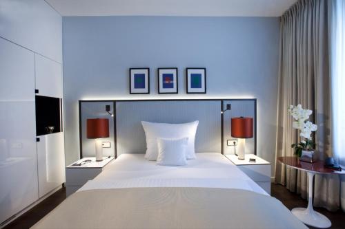 um quarto com uma grande cama branca e 2 candeeiros em AMERON Bonn Hotel Königshof em Bona