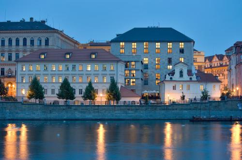 un grupo de edificios junto a un río por la noche en Four Seasons Hotel Prague, en Praga