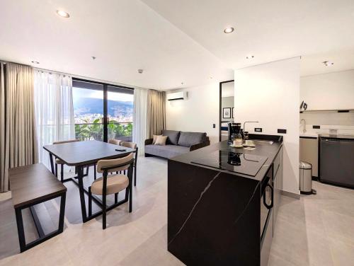 メデジンにあるLaureles Selection Suitesのキッチンとテーブルとソファのあるリビングルーム