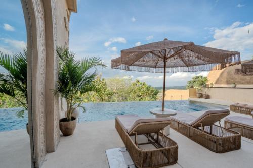 ウルワツにあるSunny Samudraのパティオ(椅子、パラソル、プール付)