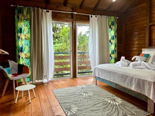 een slaapkamer met een bed en een groot raam bij La Palmeraie du Carbet in Capesterre-Belle-Eau