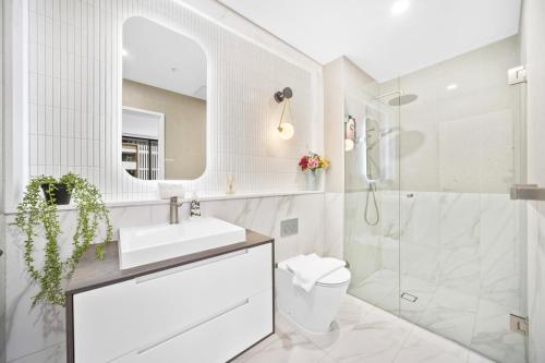ein weißes Badezimmer mit Waschbecken und Dusche in der Unterkunft Modern 2Bed 2bath 1 multipurpose room apartment 350m to Kogarah Station 15min train to airport in Sydney