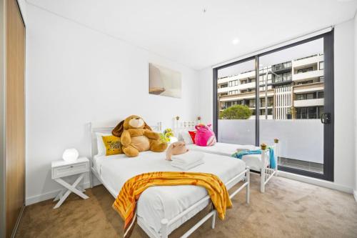 ein Schlafzimmer mit zwei Betten mit einem Teddybär drauf in der Unterkunft Modern 2Bed 2bath 1 multipurpose room apartment 350m to Kogarah Station 15min train to airport in Sydney