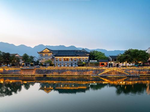een brug over een waterlichaam met een gebouw bij SSAW Garden Hotel Ningbo Xikou in Fenghua