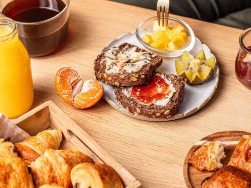 Ein Tisch, gedeckt mit einem Teller Brot und Orangenscheiben. in der Unterkunft Mercure Hotel Koblenz in Koblenz