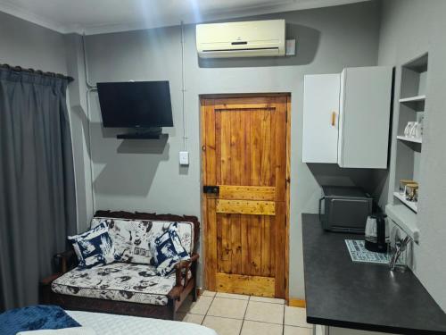 Habitación con puerta, sofá y TV en WegkruiperQ, en Beaufort West