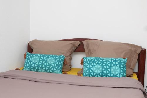 a bed with three pillows on top of it at Kaz mahury zen-wifi-climatisation in Rémiré