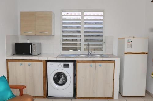 a kitchen with a washing machine and a sink at Kaz mahury zen-wifi-climatisation in Rémiré