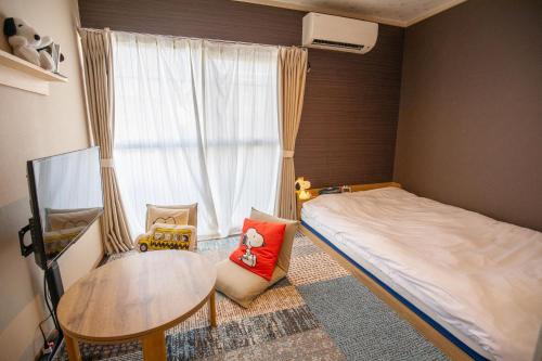 a bedroom with a bed and a table and a window at Guesthouse Life Field in Kurashiki
