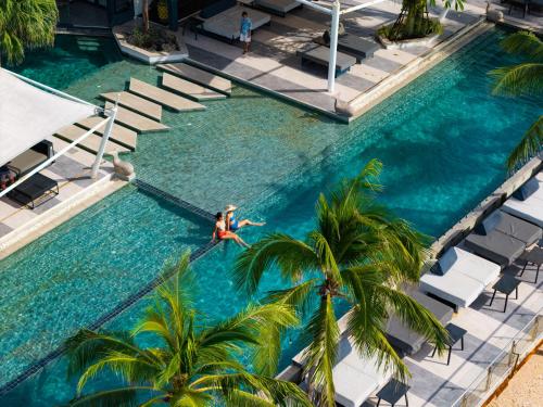 a woman swimming in a swimming pool with palm trees at Hotel Tide Phuket Beachfront in Phuket Town