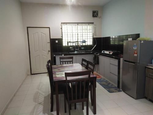 een keuken met een tafel, stoelen en een koelkast bij Teratak Desa Cemerlang 1 