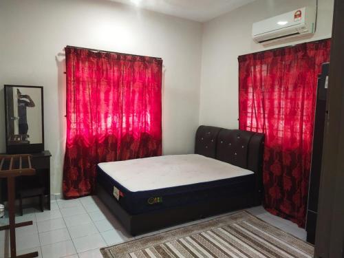 een slaapkamer met een bed en rode gordijnen bij Teratak Desa Cemerlang 1 