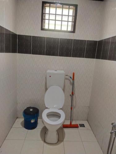 a bathroom with a white toilet and a window at Teratak Desa Cemerlang 1 in Enggur