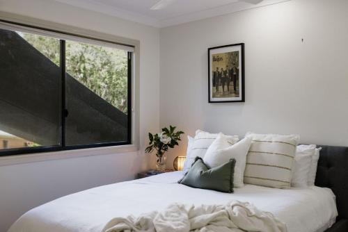 a bedroom with a white bed with a large window at Bayview Beach House - Pet Friendly Holiday Home with a Pool - Holiday Yamba in Yamba