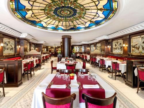 拉巴特Le Diwan Hotel Rabat - MGallery Collection的餐厅设有桌椅和彩色玻璃天花板