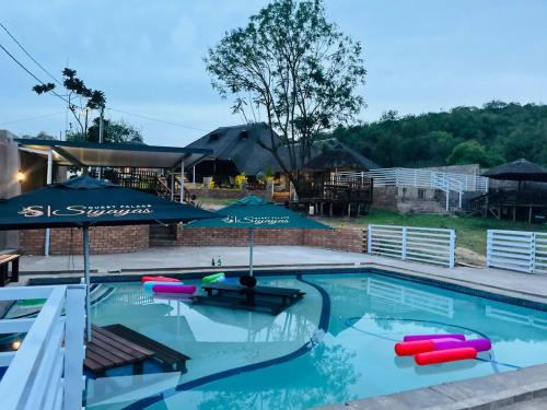 a swimming pool with an umbrella and inflatables in it at Siyaya’s Guest Palace in Jozini