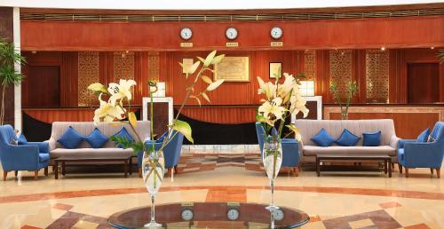 a lobby with chairs and a table and vases with flowers at JAZ Royal Palmariva in Hurghada