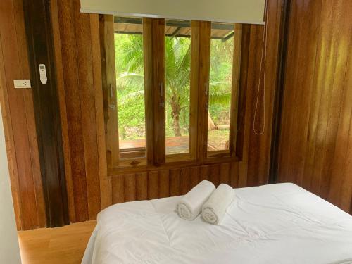a bedroom with two towels on a bed with a window at Baan Phuean Koh Kood in Ko Kood