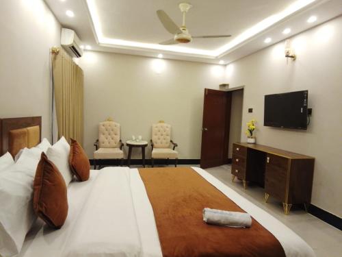 Blue Sky Hotel Clifton 2 في كراتشي: غرفة نوم بها سرير كبير وتلفزيون