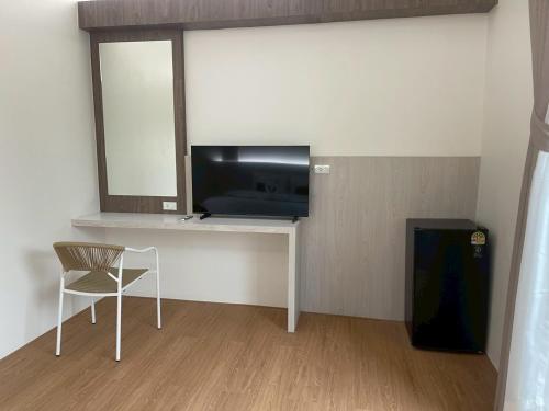 een kamer met een bureau, een televisie en een stoel bij Salty Sand Krabi Hotel in Ban Khlong Haeng