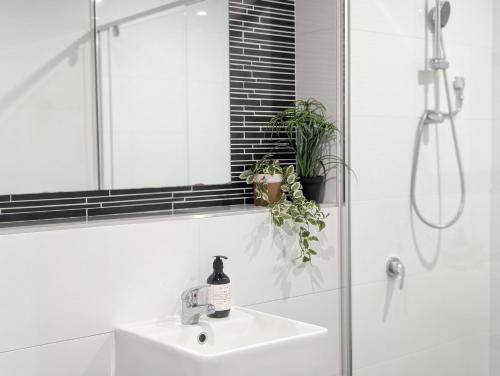 a white bathroom with a sink and a mirror at Modern & Relaxed Apartment, Great Views @Wright in Weston Creek
