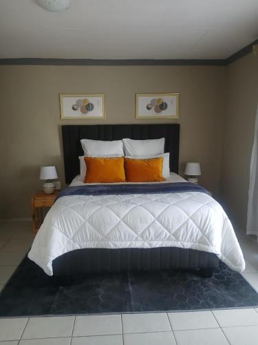 a bedroom with a large bed with orange pillows at Nuday Guesthouse in Vaalwater
