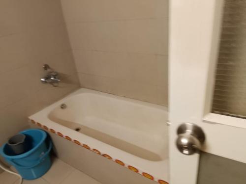 a bathroom with a white tub and a blue bucket at Ksr woodland Residency in Kodaikānāl