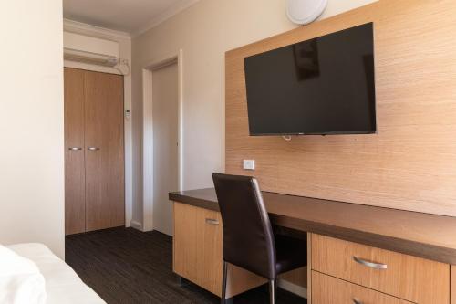 um quarto com uma secretária e uma televisão na parede em Sphinx Hotel em Hamlyn Heights