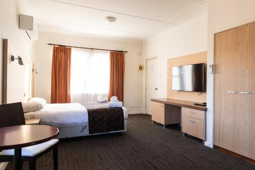 um quarto de hotel com uma cama e uma televisão em Sphinx Hotel em Hamlyn Heights