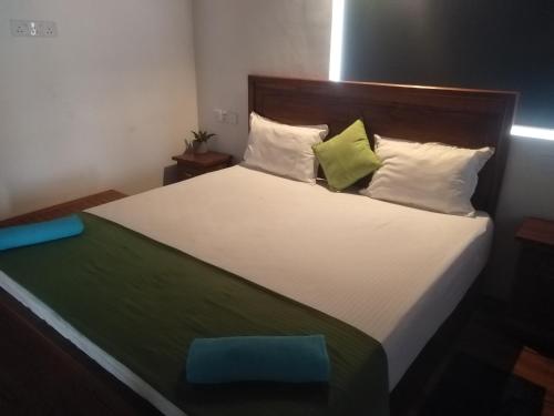 a bedroom with a large bed with green and white pillows at Solace Transit Villa in Katunayake