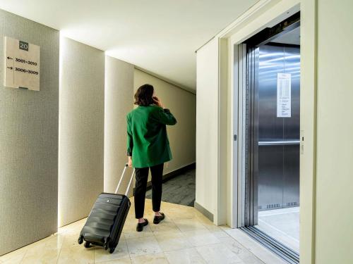 圣保罗Mercure São Paulo Ibirapuera Privilege的带着手提箱走下走廊的女人