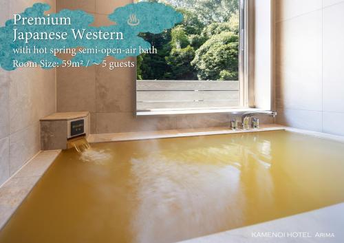 a bath tub filled with water next to a window at KAMENOI HOTEL Arima in Kobe
