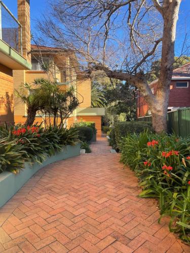 a brick walkway in front of a building with flowers at Cronulla courtyard unit, 10 mins walk to Beach & Bay in Cronulla