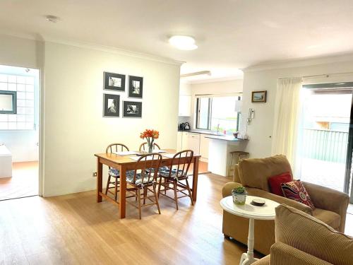 una sala de estar con una mesa y un sofá en Cronulla courtyard unit, 10 mins walk to Beach & Bay, en Cronulla