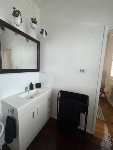 a white bathroom with a sink and a mirror at Urbane on William in Rockhampton