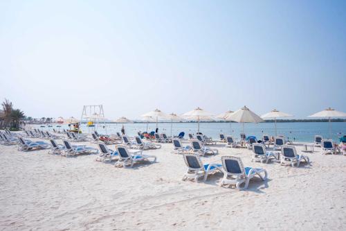 a group of chairs and umbrellas on a beach at Yas Island Mayan 2 Junior 1 Bed Apartment by Central Stay in Abu Dhabi