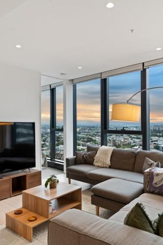 a living room with a couch and a tv at Skyline City Views with 75 Inch TV & Pool Gym Sauna in Melbourne
