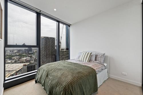 a bedroom with a bed and large windows at Skyline City Views with 75 Inch TV & Pool Gym Sauna in Melbourne