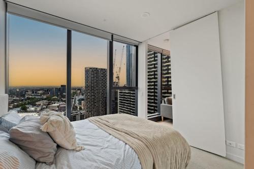 a bedroom with a bed with a view of a city at Skyline City Views with 75 Inch TV & Pool Gym Sauna in Melbourne