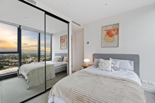 a bedroom with two beds and a large window at Skyline City Views with 75 Inch TV & Pool Gym Sauna in Melbourne
