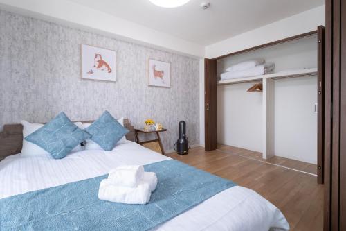 a bedroom with a large white bed with blue pillows at The Peak Tengachaya in Osaka