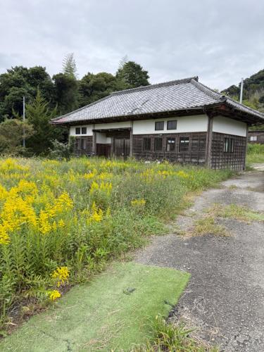 an old house with a field of flowers in front of it at Oasis Minamiboso in Minamiboso