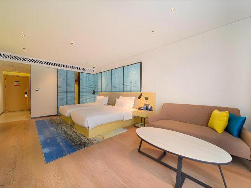 a bedroom with a bed and a couch and a table at Echarm Hotel Foshan West Station Shishan Luocun in Luocun