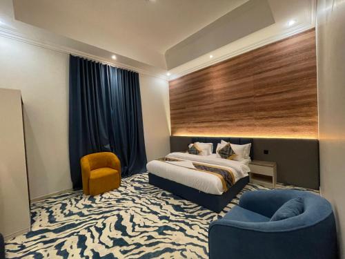 ein Hotelzimmer mit einem Bett und einem blauen Stuhl in der Unterkunft ايفان شقق المخدومة العوالي in Quai