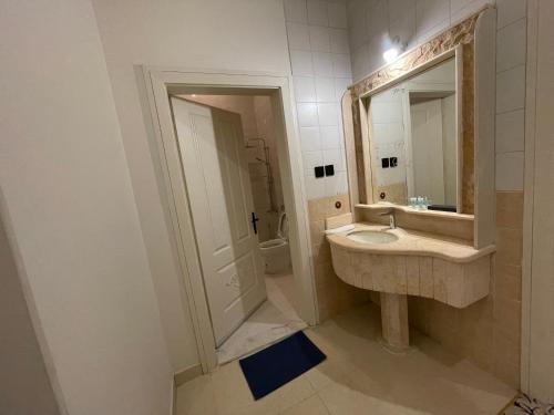 ein Badezimmer mit Waschbecken, Dusche und Spiegel in der Unterkunft ايفان شقق المخدومة العوالي in Quai