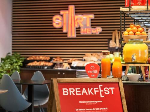 a restaurant with a breakfast buffet with orange juice at Ibis Madrid Calle Alcalá in Madrid