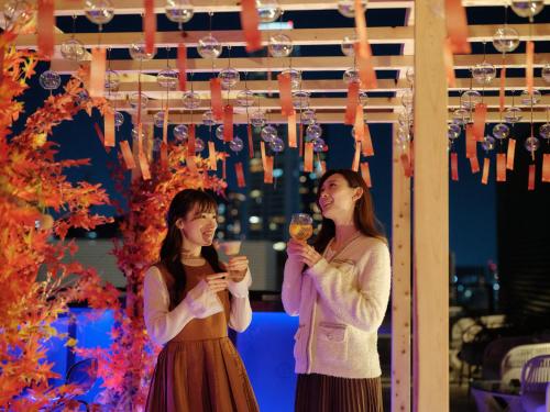 two women laughing while holding glasses of wine at The Lively Osaka Honmachi in Osaka