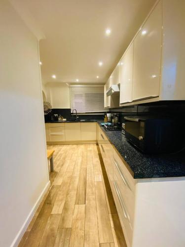 a kitchen with white cabinets and a wooden floor at Relax in this Charming East Cowes House with Garden and BBQ in East Cowes